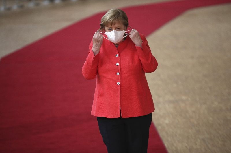 German Chancellor Angela Merkel prepares to remove her protective mask to make a statement as she arrives for an EU summit at the European Council building in Brussels. (Photo by Francisco Seco/AP Photo/Pool)
